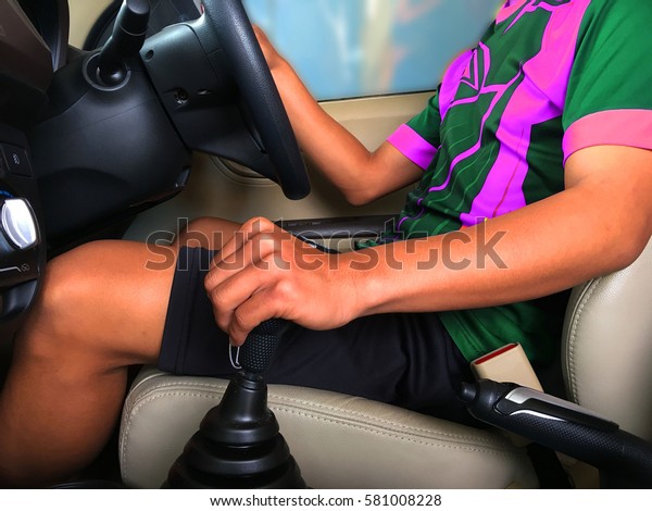 Man driving a car and\
change gears.