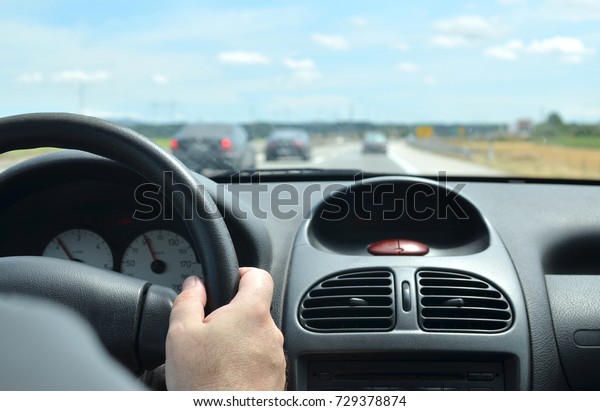 Man\
driving a car with a dirty front glass after a long drive on a\
highway with other vehicles blurred in front of\
him