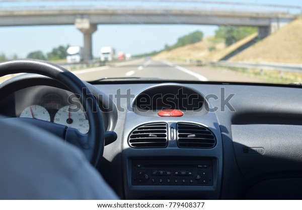 Man driving a car\
with a dirty front glass after a long drive on a highway with a\
viaduct in front of him