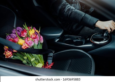 Man Driving A Car With Flowers Next To Him In Passengers Seat