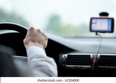 Man Driving A Car With His Hands On The Steering Wheel, Using A Satelite Navigation/GPS