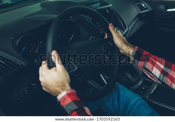 Man driving a car with his two hands on the\
steering wheel