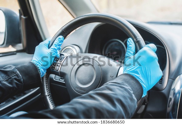 Man driving a car in medical gloves.\
Covid-19 concept, coronavarius. Virus\
protection