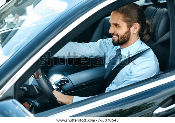 Man Driving Car. Portrait Of Smiling Male\
Driving Car. Successful Young Business Man Going To Work In\
Comfortable Auto. High\
Resolution.