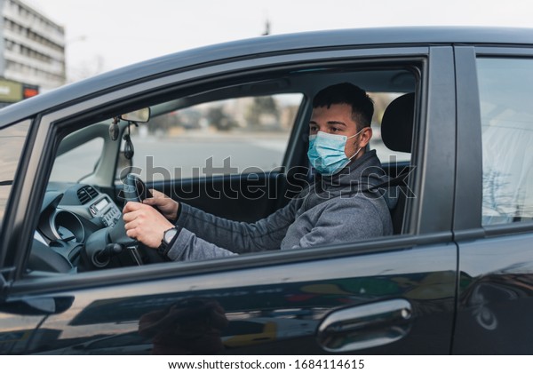 a\
man driving a car puts on a medical mask during an epidemic, a taxi\
driver in a mask, protection from the virus. Driver in black car.\
coronavirus, disease, infection, quarantine,\
covid-19