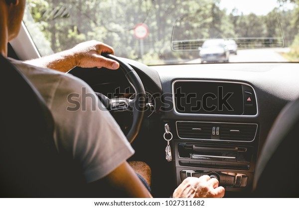 Man driving\
car from rear view on the\
highway.