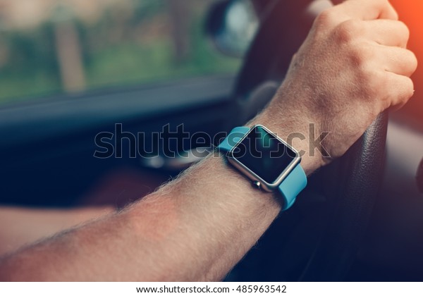 Man driving a car,\
smart watch on his hand