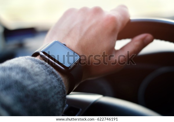 man driving a\
car with smart watch on the\
hand