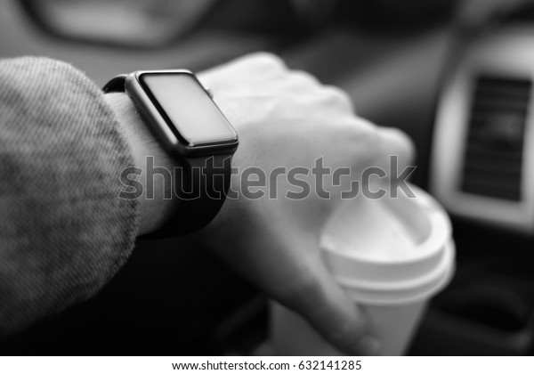 man driving a\
car with smart watch on the\
hand