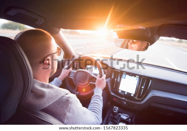 Man driving a\
car. Success in motion. Handsome young man driving a car. A man\
holds the steering wheel of a\
car.