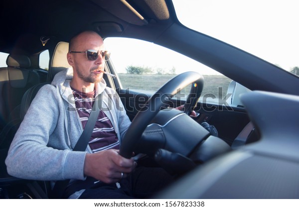 Man driving a car.\
Success in motion. Handsome young man driving a car. A man holds\
cigarette while driving.