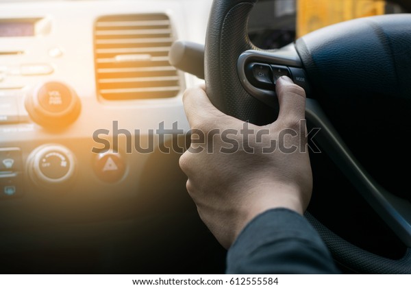 Man driving car and\
turn down the volume.