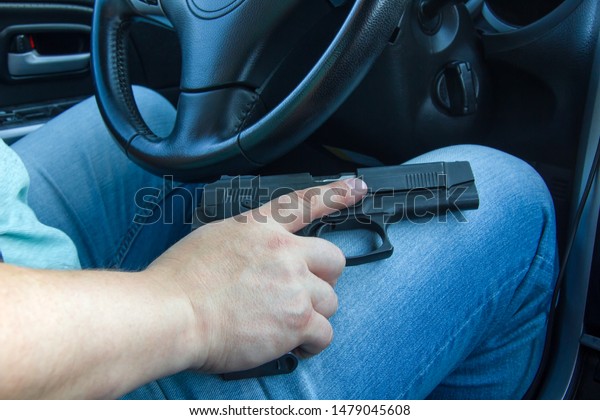 Man driving a car\
with a weapon, gun in his hand. The criminal steals the car. Danger\
district of the city