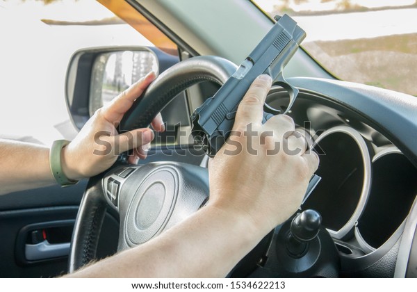 Man driving a car\
with a weapon, gun in his hand. The criminal steals the car. Danger\
district of the city 