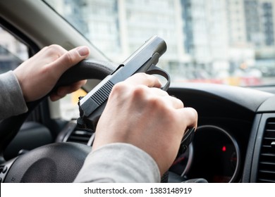 man driving a car with a weapon in his hand. the criminal steals the car. criminal district of the city - Shutterstock ID 1383148919