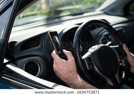 Man driving a car while using a smartphone, representing the danger of distracted driving and lack of attention on the road.