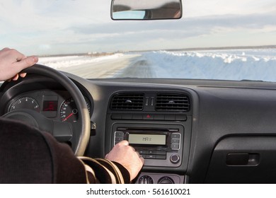 Man Driving A Car, Driving In Winter On Snow-covered Road In Front Of The Sunset. Listening To Music Adding To The Maximum Sound. Vehicle Management, Interior.