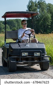 Man Driving A Custom Golf Cart Down A Gravel Road, Canada. 