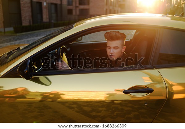 A man driving\
an expensive car. A man is driving, a successful man is driving a\
car. Golden yellow car. A man at sunset driving. Success,\
expensive, freelance, businessman,\
famous.