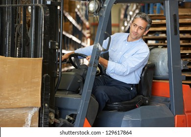 Man Driving Fork Lift Truck In Warehouse