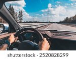 Man driving modern car from rear view on the highway. Hands on the steering wheel.