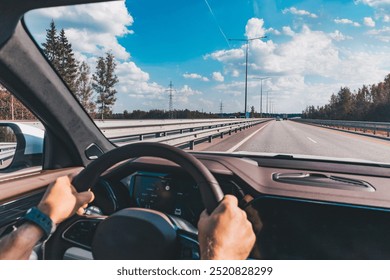 Man driving modern car from rear view on the highway. Hands on the steering wheel.