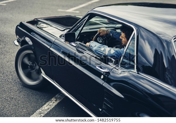 A man driving old black\
stylish car