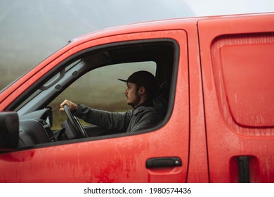 Man driving a red van while raining
