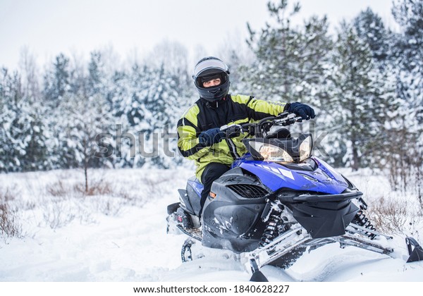 Man driving snowmobile in\
snowy forest. Man on snowmobile in winter mountain. Snowmobile\
driving.