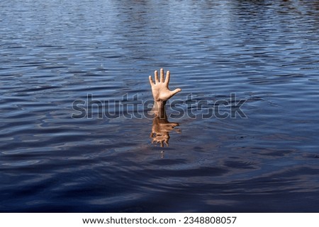 a man is drowning, his hand is sticking out of the water	
