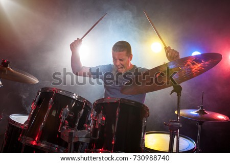  man drummer playing drums with passion over dark background