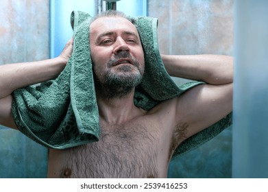 Man drying himself after getting out of the shower. Man using towel in a bathroom. Man wipes his body with a towel