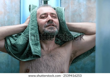 Man drying himself after getting out of the shower. Man using towel in a bathroom. Man wipes his body with a towel