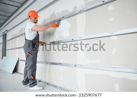 man drywall worker using trowel for plasterer putting stucco on plasterboard white wall