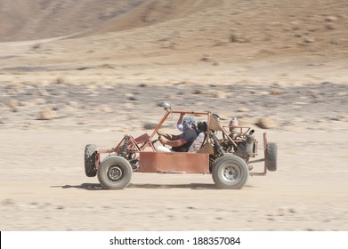 Man In A Dune Buggy Racing Across Desert Landscape At Speed With Motion Blur