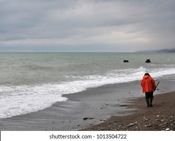 a man during a storm looking for seashells