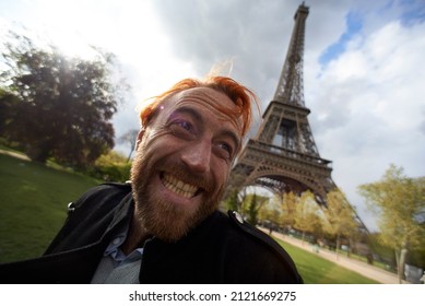Man with dyed orange hair super excited to be visiting the Eiffel Tower in the city centre of Paris