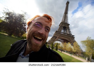 Man with dyed orange hair super excited to be visiting the Eiffel Tower in the city centre of Paris