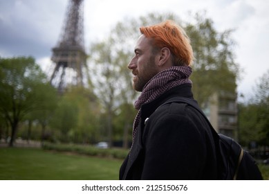 Man with dyed orange hair walking near the Eiffel Tower in Paris