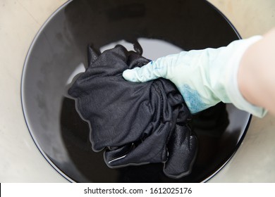 man dyeing clothes in bucket - Shutterstock ID 1612025176