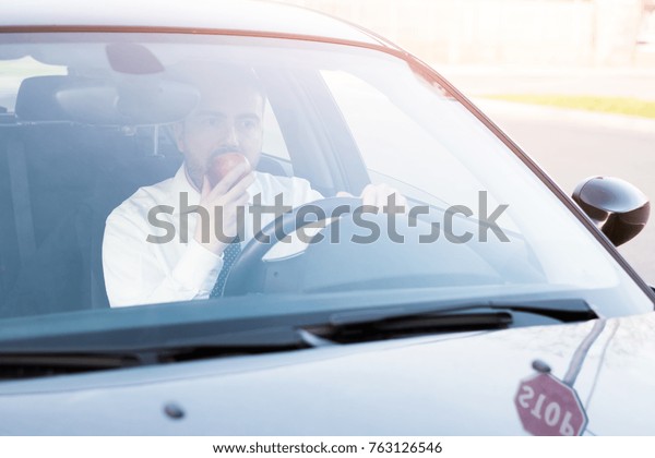 Man eating an apple\
driving in his car