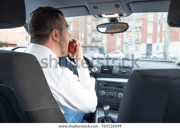 Man eating an apple
driving his car