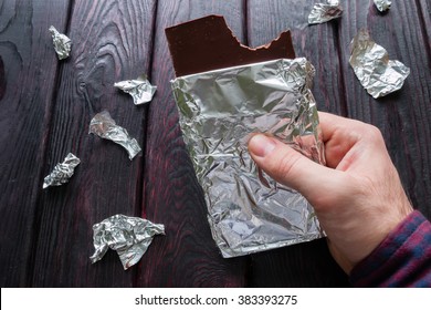 Man Eating A Bar Of Chocolate On A Black Background