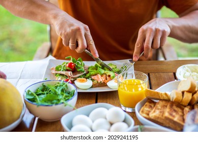 Man Eating Breakfast Toast With Egg.Toast For Breakfast.Breakfast In The Hotel.Home Cooked Healthy Food.Toast With Avocado, Arugula And Ham.Avocado Toast.Lunch At Work.Breakfast Outside.Orange Juice