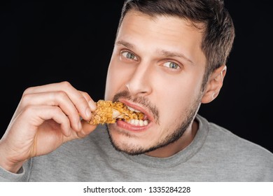 Man Eating Crispy Chicken Nugget While Looking At Camera Isolated On Black