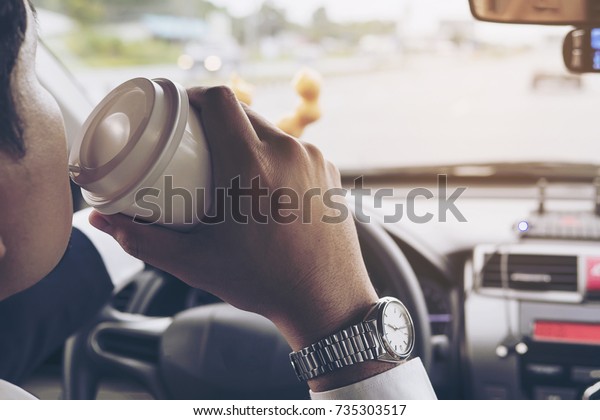 Man eating donuts with coffee while\
driving car - multitasking unsafe driving\
concept