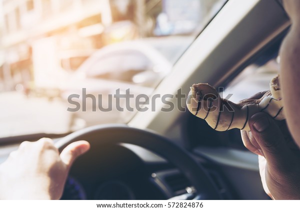 Man eating donuts while driving car -\
multitasking unsafe driving\
concept