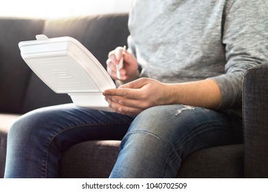 Man Eating Fast Food From Take Away Box Home On Couch. Takeout Dinner From Chinese Or Junk Food Restaurant. Guy Enjoying Kebab Or Salad.