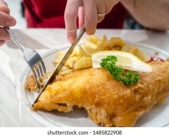 Man Eating Fish And Chips With A Slice Of Lemon And Garnish Of Greenery, Traditional English Dish