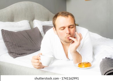 A Man Is Eating Food In Bed. The Guy Licks His Fingers For Food With His Eyes Closed. Tasty Breakfast. Real Jam.